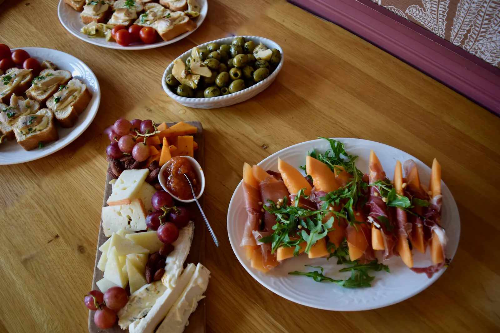 A full aperitivo table at Struis with crostini, olives, cheese and prosciutto with melon